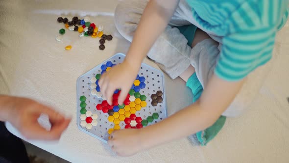 Children's Hands and the Hands of an Adult Play a Children's Game Collect a Colored Mosaic on a