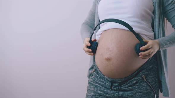 Pregnant Woman Puts Wireless Headphones on Tummy at Wall