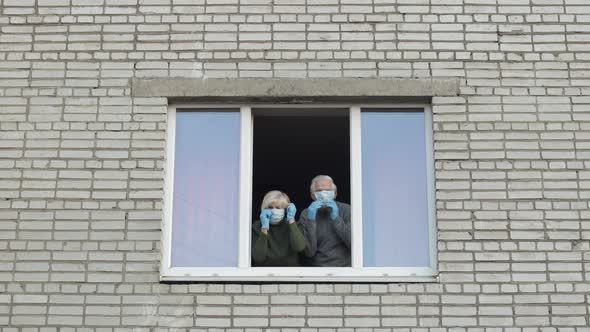 Old Grandparents Stay at Window Isolated at Home on Quarantine. Coronavirus