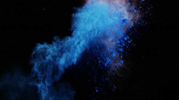 Blue and red dust powder blowing against black background