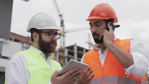 Engineer Speaks on Mobile Phone on Construction Site and Checks the Work of the Worker. Builder