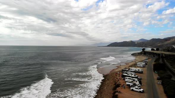 Aerial drone shot over the State Beaches in Ventura with surfers and RV campers next to the busy Cal