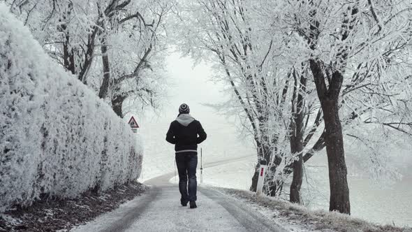 Anonymous man walking on snowy path