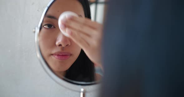 Cute Beautiful Natural Brunette Asian Girl Cleaning Face with Cotton Sponge Smiling Looking at Her