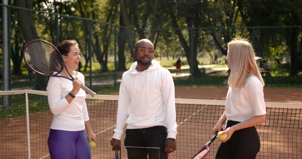 Three Multi Racial Tennis Players Talking on Court