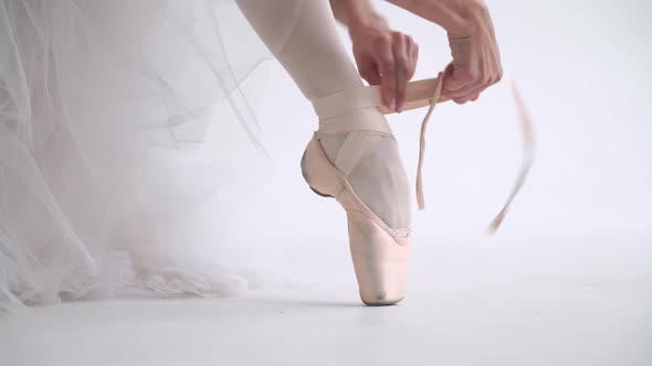 Female in a White Tutu Sits on the Floor and Ties the Ribbons of Her Pointe Shoes, Young Ballerina