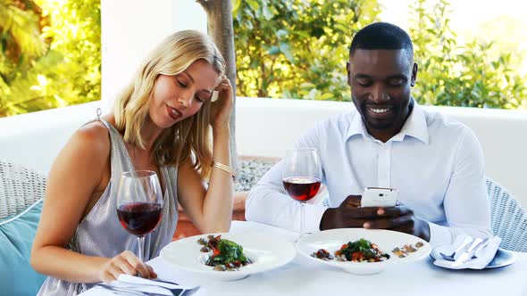 Man ignoring bored woman while using mobile phone