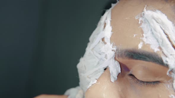 Make up artist applying white prosthetic insert on man's face to make a Halloween mask