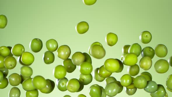 Super Slow Motion Shot of Flying Fresh Green Olives on Light Green Gradient Background at 1000 Fps.