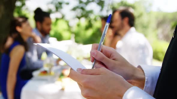 Waitress writing on note pad at outdoor restaurant