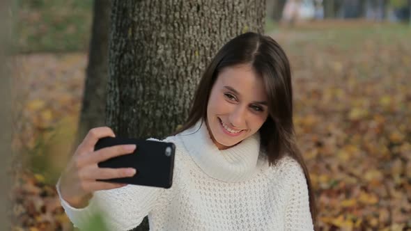 Girl Makes Selfie in the Autumn Park