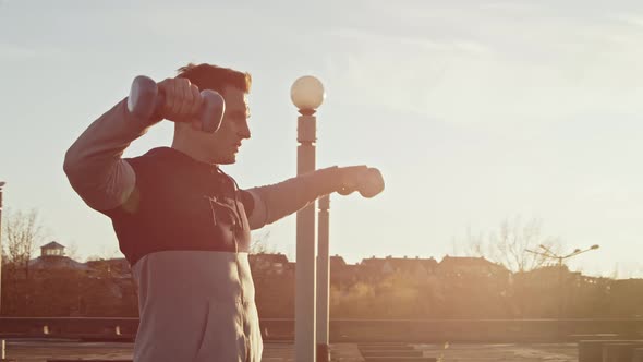 Young and fit man having evening workout outdoor. Urban sunset background.