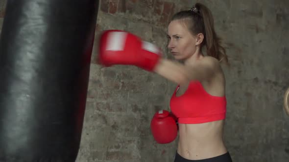 Woman in Boxing Gloves Beats a Punch Bag