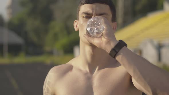 Close-up of Handsome Brunette Sportsman Drinking Water and Leaving. Portrait of Serious Caucasian