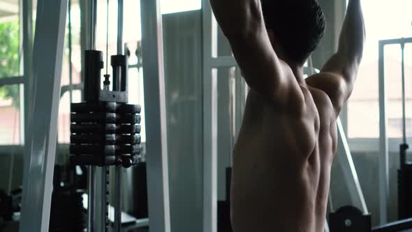 Fit Man Working Out on Lat Pull Down Machine at the Gym