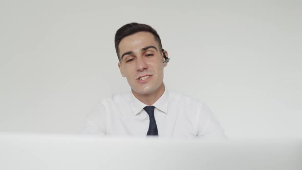 Happy Male Student with Earset Passes the Exam Online Remotely on a Laptop