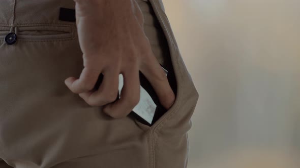 Man Takes Mobile Phone From His Trousers Pocket. Man Hand Put Mobile Phone In Back Pocket.