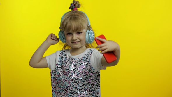 Child Dances with Smartphone, Listening To Music on Headphones. Little Kid Girl Dancing, Having Hun