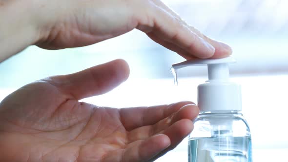 Male Hands Push the Dispenser and Squeeze Out Liquid Soap