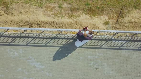 Newly Wedded Couple Kisses Near Railing Over Hill Upper View