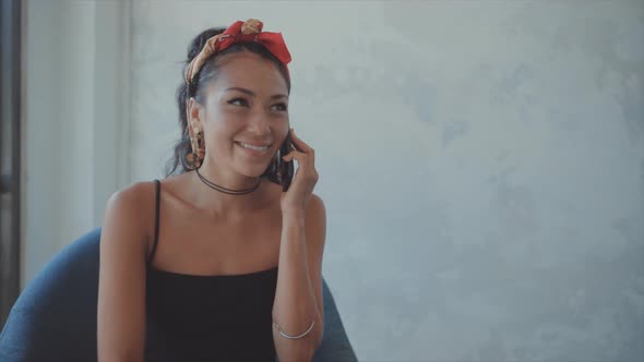 Woman Holding a Cup of Coffee Laughs As She Talks on Her Cellphone