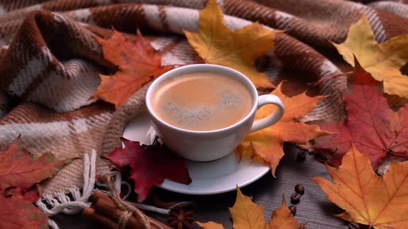 Autumn Fall Leaves Hot Cup of Coffee and Warm Plaid on a Wooden Table Background