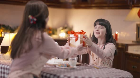 Excited Little Daughter Receiving Christmas Present on New Year's Eve From Mother