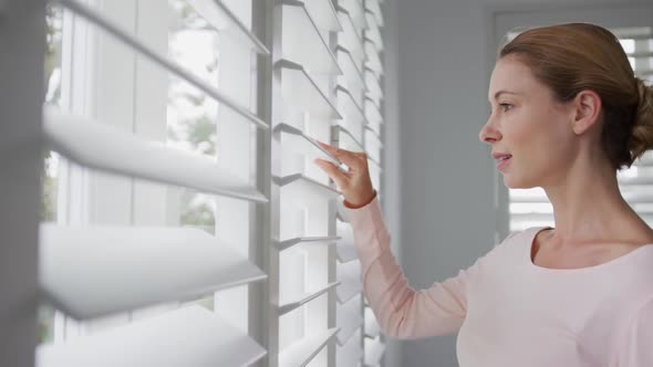 Woman looking outside through window at comfortable home 4k