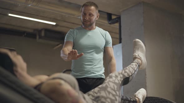 Positive Smiling Man Training Sportswoman Doing Gravity Exercise. Confident Adult Caucasian Trainer