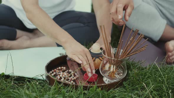 Closeup of Aroma Sticks and Candles on a Wooden Plate on the Grass