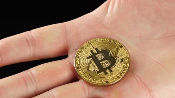 Golden Bitcoin in a Man's Hand, Symbol of a New Virtual Currency