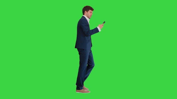 Serious Businessman Using Phone Voice Dial While Walking on a Green Screen, Chroma Key