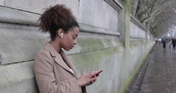 Female tourist using smartphone and listening to music in London