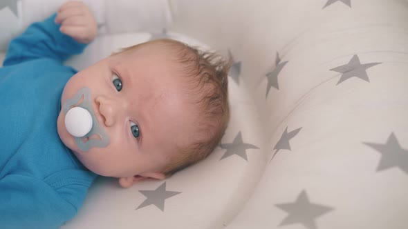 Small Kid with Pacifier Rests in Sleeping Cocoon Closeup