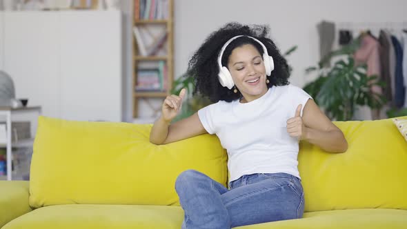 Portrait of a Young African American Woman Enjoys Music with Big White Headphones