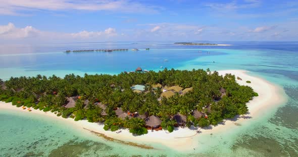 Aerial drone view of a scenic tropical island resort hotel in the Maldives.