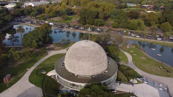 drone flight over the planetario building in buenos aires argentina with the busy road and lakes in