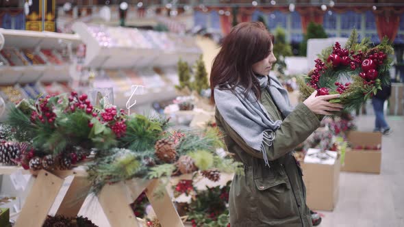 A Young Beautiful Woman Walks Around the Store and Selects Christmas Decorations and Decorations to