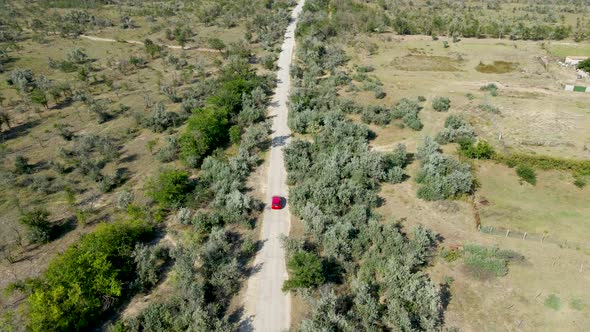 a Red Passenger Car Drives on a Shroud on a Concrete Road