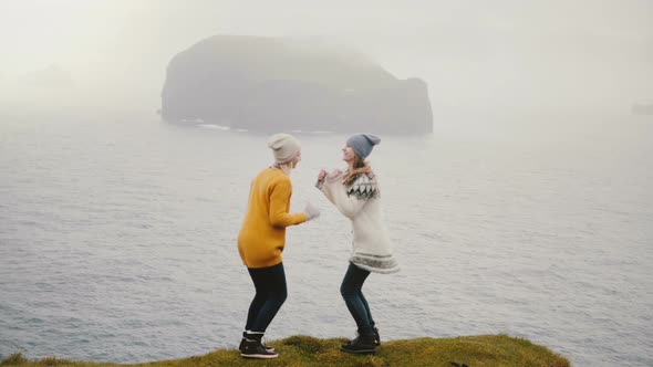 Two Happy Traveling Woman Dancing a Crazy Dance on the Shore of a Sea, Cheerful Female Having Fun