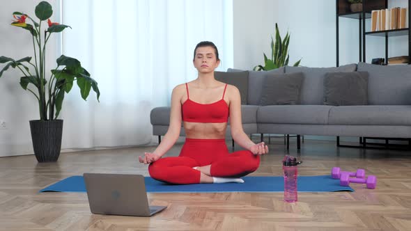 Beautiful Fit Girl Sits Meditating in Lotus Position on Sport Fitness Blue Mat