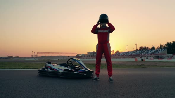 Professional Racer in Sportswear is Standing Next to a Racing Cart