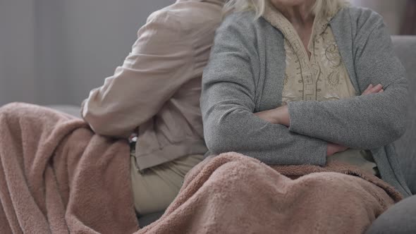 Unrecognizable Old Woman Crossing Hands Sitting Back to Back with Friend on Couch Indoors