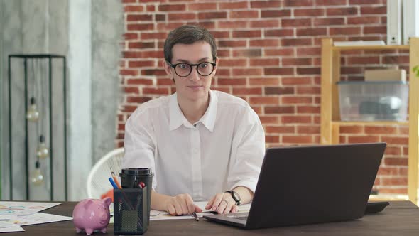 Businesswoman in a White Shirt Takes Off Glasses and Negatively Moves Head Sitting at a Desk in the