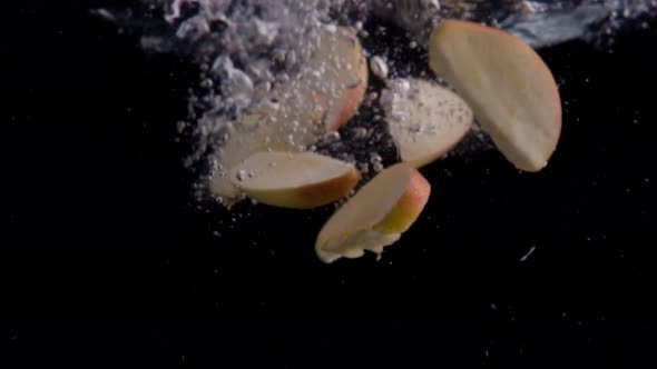 Apple Slices Falling into Water Super Slowmotion, Black Background, lots of Air Bubbles, 4k240fps