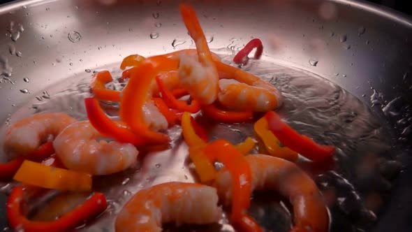 Peeled Shrimps and Peppers Are Falling on the Heated Olive Oil on the Frying Pan