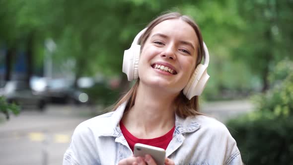 Cute girl in white, wireless headphones smiling sincerely