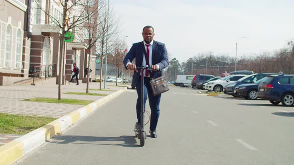 Black Businessman Riding on Electric Scooter on City Street