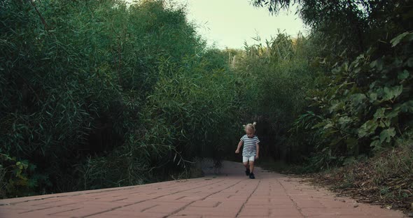 Cute Little Girl Running Outdoors in Park on Summer Evening