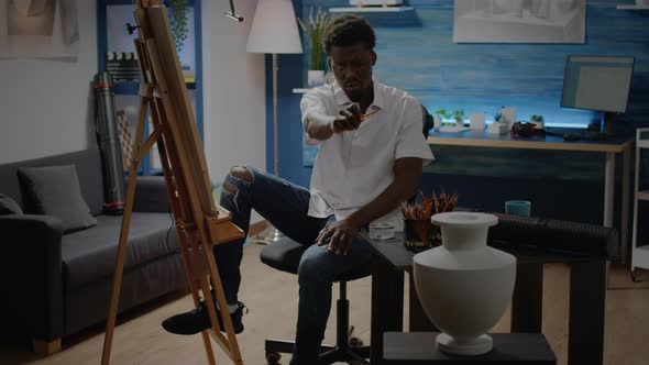African American Man Studying Vase Design with Pencil